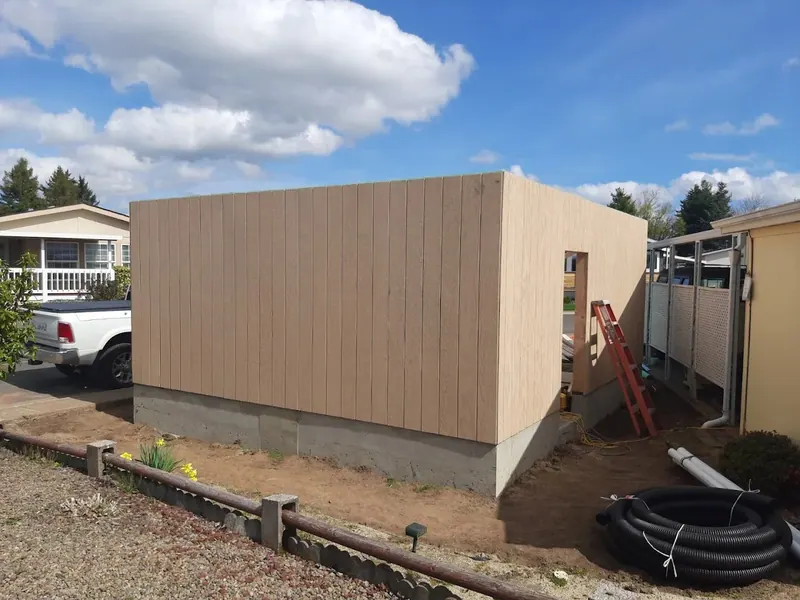 A new detached garage or shop building with vertical board-and-batten siding being constructed on a concrete block foundation, Red Umbrella Eugene Oregon.