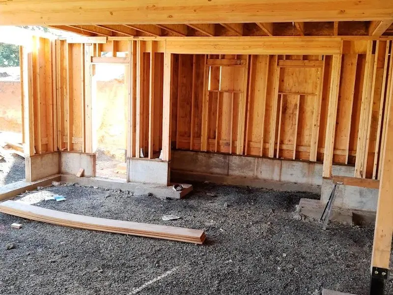 Interior framing of a new home addition viewed from the foundation level, showing floor joists and stud walls on a Red Umbrella construction project.