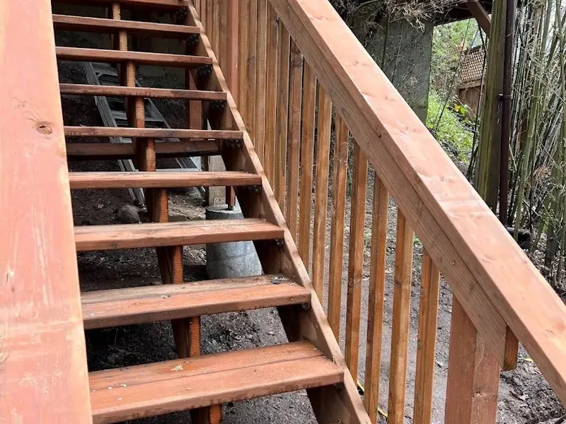 Newly built cedar deck staircase with vertical baluster railing descending through a bamboo-lined garden, built by Red Umbrella.