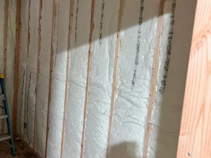 Wall stud bays fully filled with spray foam insulation during an interior build-out by Red Umbrella Contracting.
