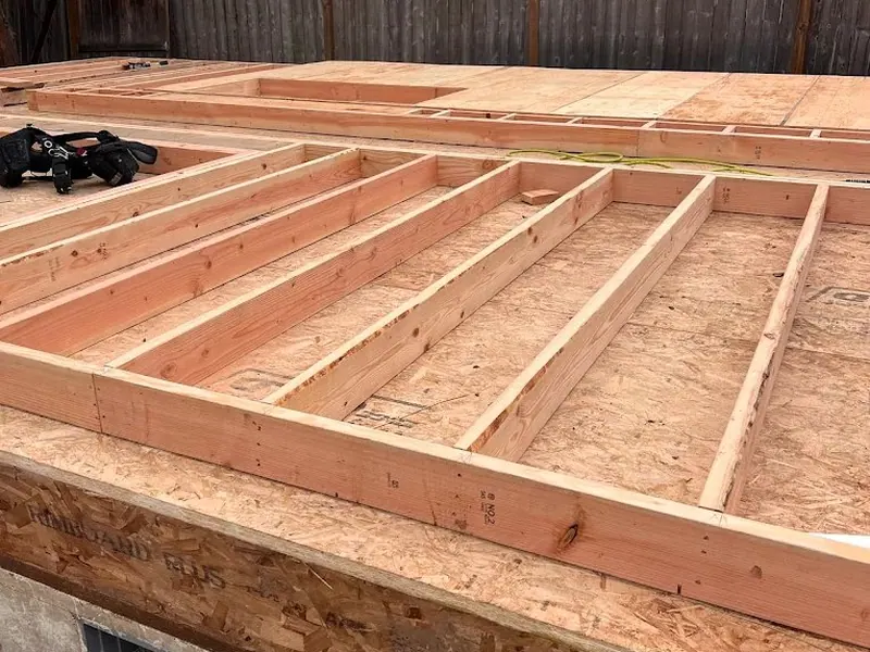 Floor joist framing laid across a concrete block foundation during an ADU or garage construction project by Red Umbrella in a Eugene residential backyard.